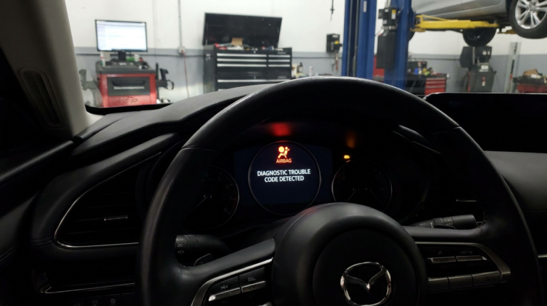Mazda dashboard with a glowing airbag warning light indicating a diagnostic trouble code alert in a professional automotive setting.