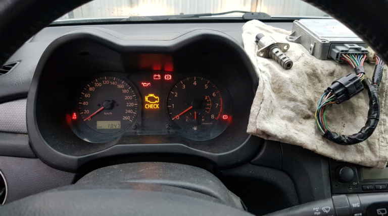 Mitsubishi vehicle dashboard with warning lights illuminated, centered on the check engine light, with VVT solenoid and ECM components included.